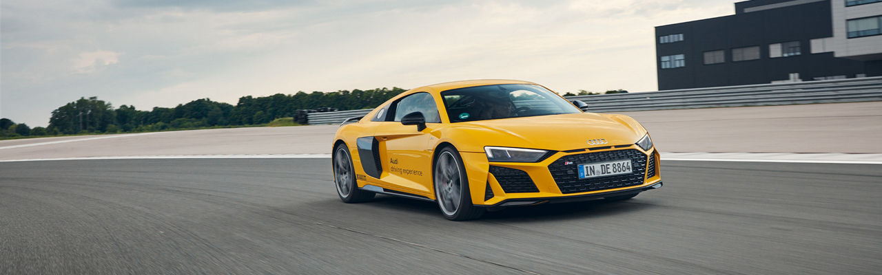 Yellow Audi R8 Coupé drives on a race track in Neuburg