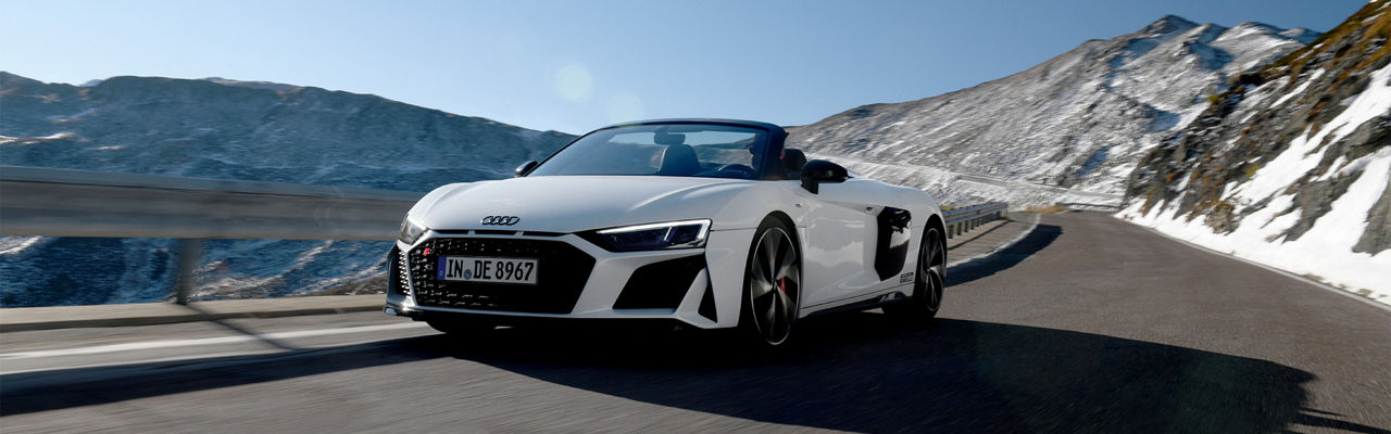White Audi R8 Spyder drives in the mountains with the top down