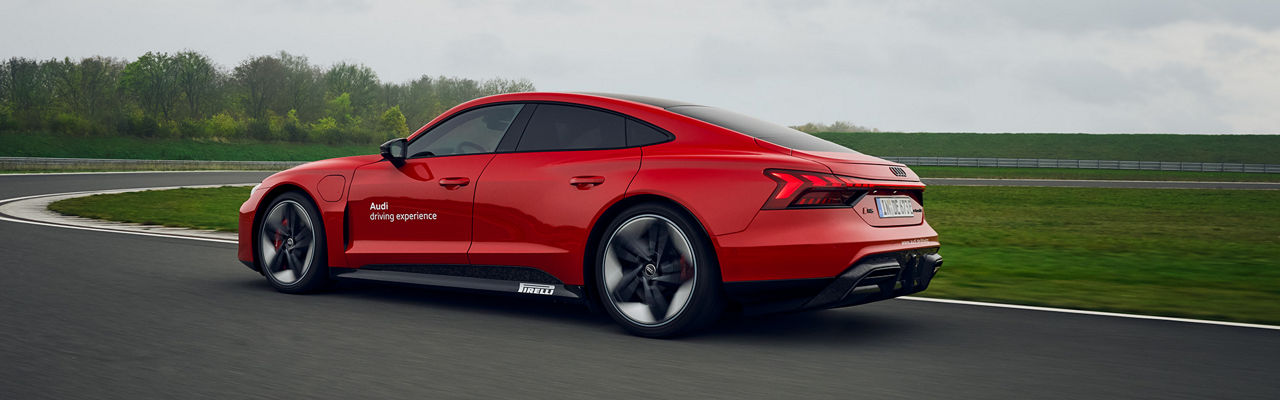 Roter Audi RS e-tron GT performance fährt auf einer Strecke (Seit-/Rückansicht)