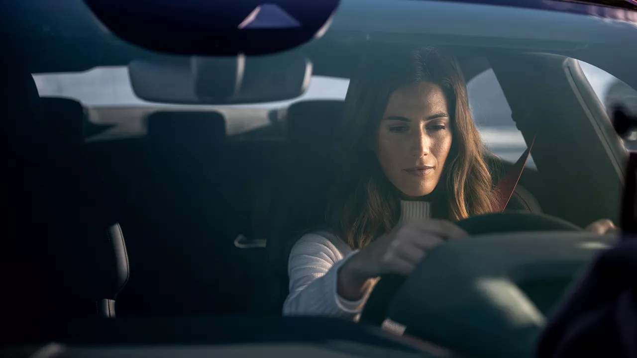 Brünette Frau sitzt in einem Auto am Steuer