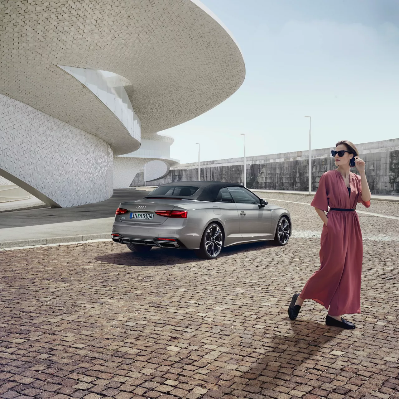 EIne Frau läuft von einem silbernen Audi weg