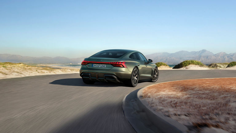 En olivgrön RS e-tron GT Performance sedd bakifrån, på en väg i ett ökenlandskap