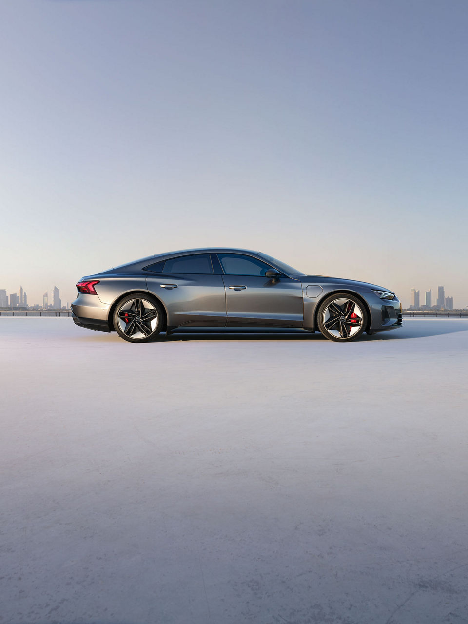 Audi RS e-tron GT sports car on a concrete surface in front of futuristic architecture