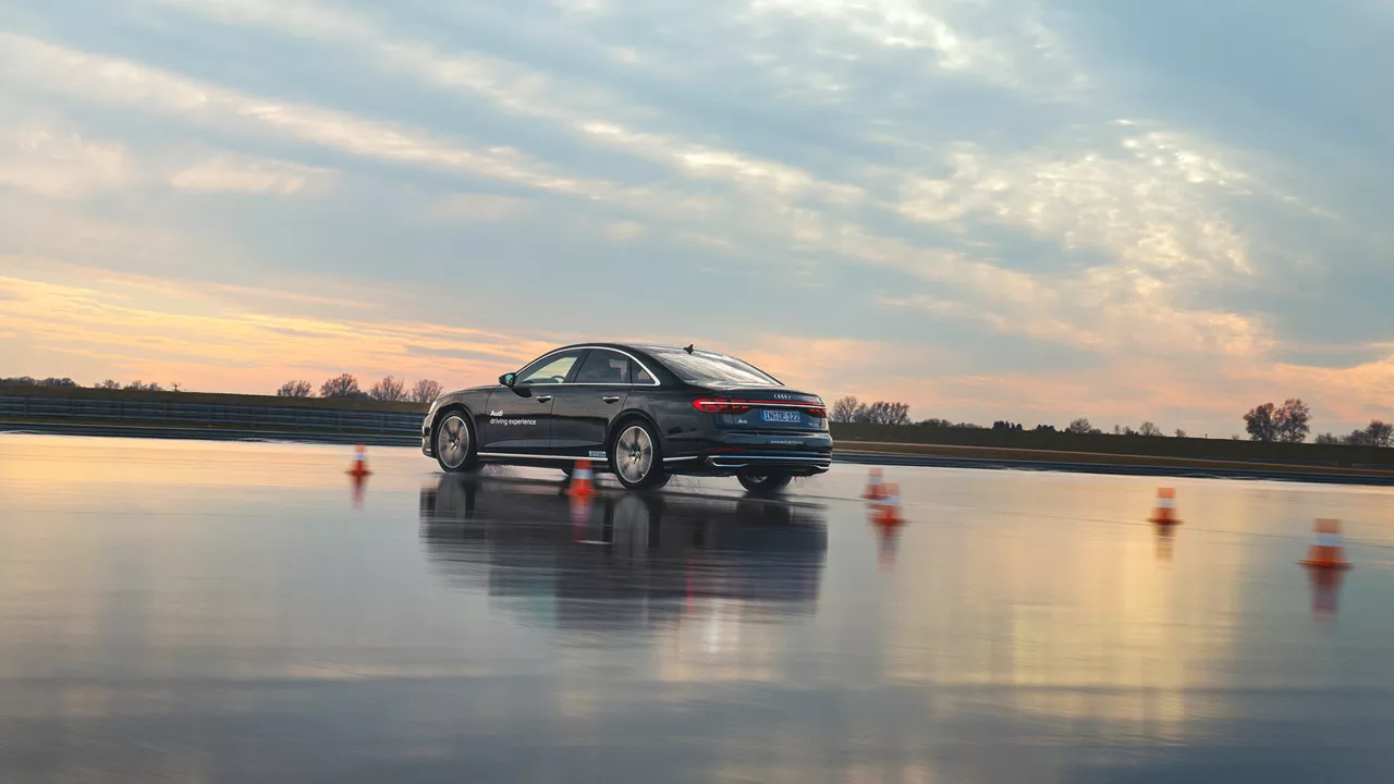 Black A8 50 TDI quattro on a wet track with course, dusk in the background