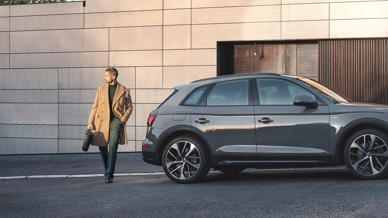 Vista di un suv Audi parcheggiato in strada, con un uomo che attraversa la strada.