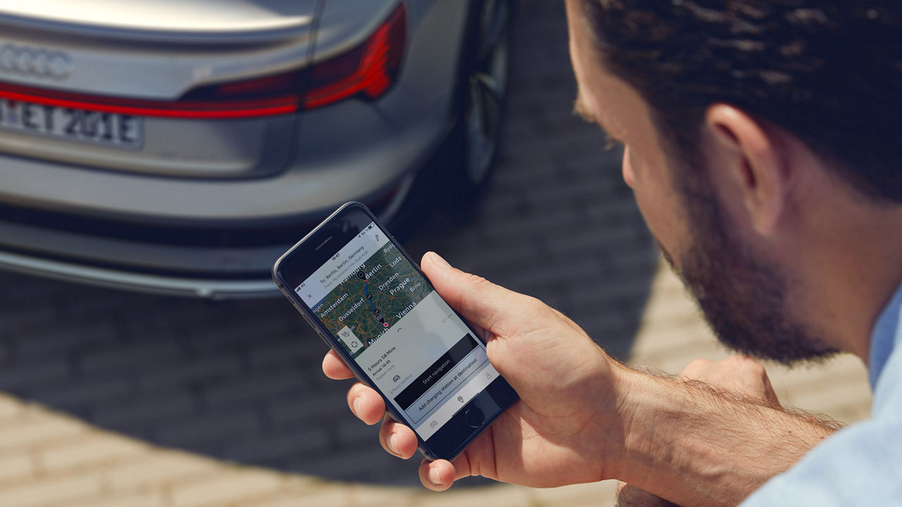 Man with smartphone in front of an Audi e-tron Sportback