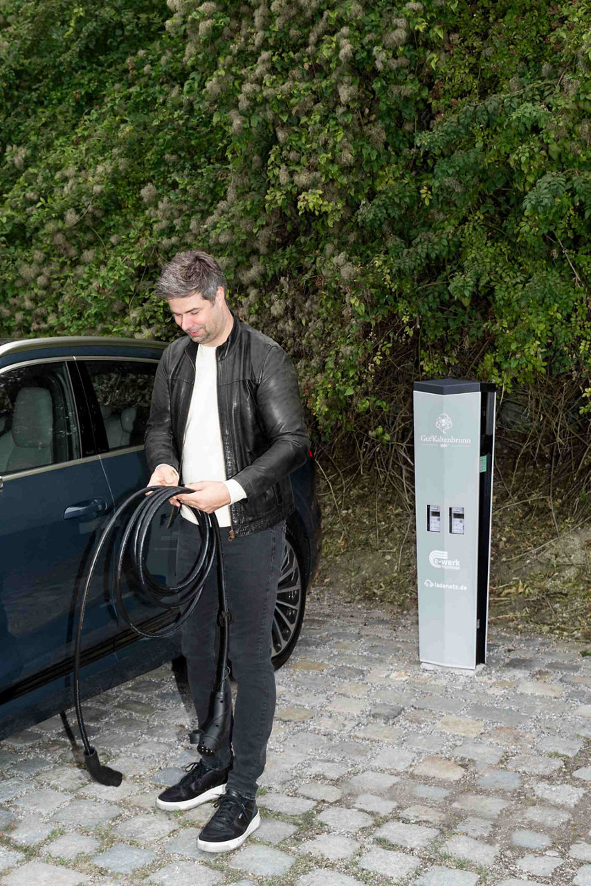 Nils Wollny trzymający w dłoni kabel ładujący.