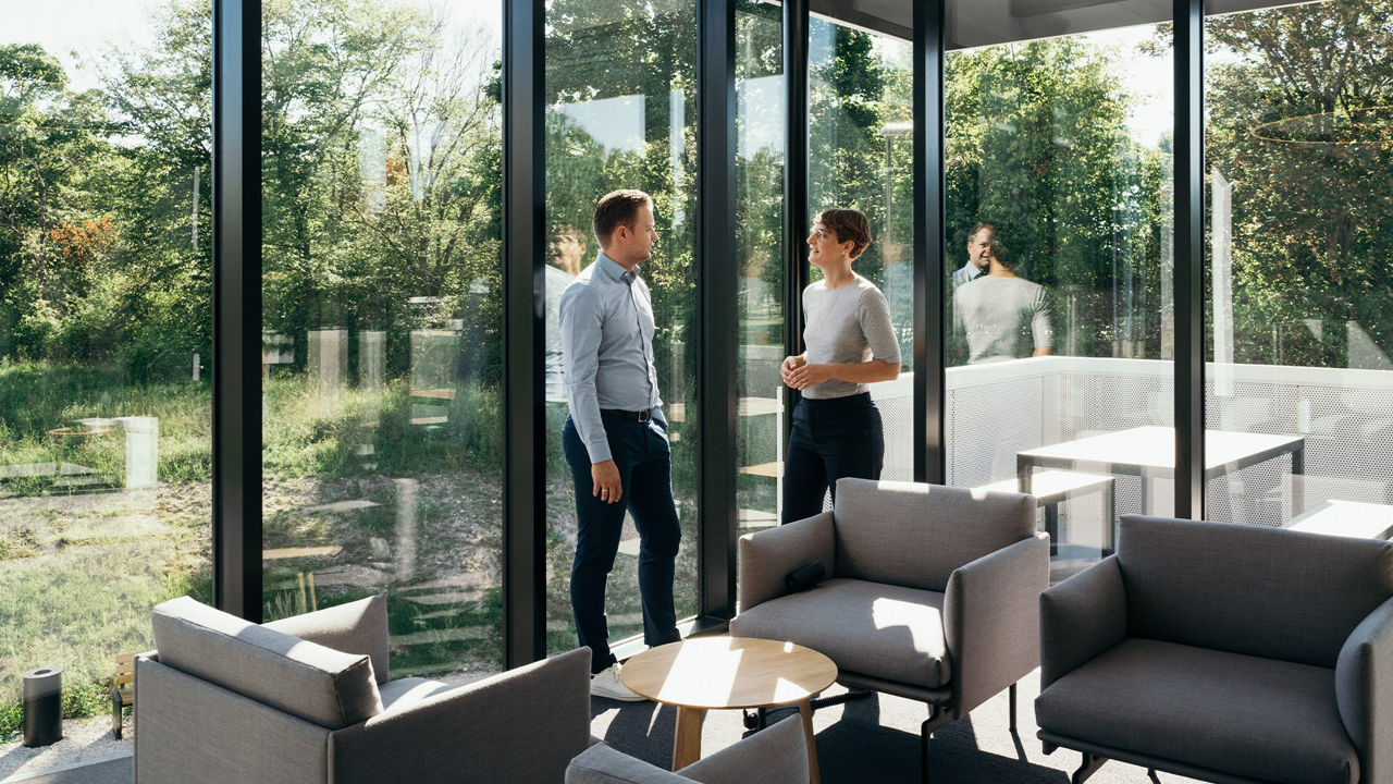 Nachhaltigkeitsexpert_innen Dr. Johanna Klewitz und Malte Vömel stehen in der Lounge des Audi charging hubs.