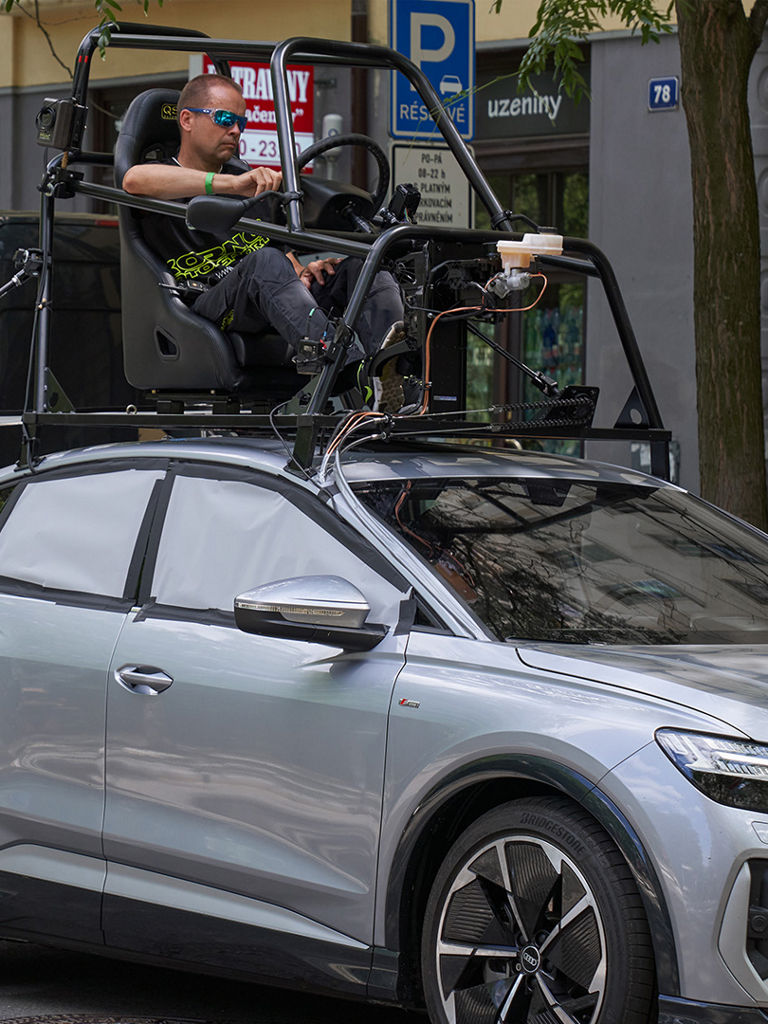 Audi Q4 e-tron Sportback czeka na planie na kręcenie sceny. Kaskadera można zobaczyć siedzącego na dachu w tak zwanym zestawie samochodowym.