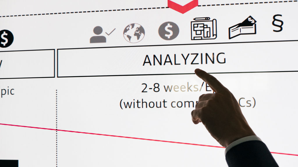 A finger points at the word “Analysing” on a screen.