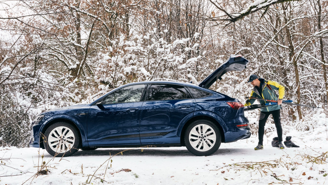 Sebastian Copeland taking ski equipment out of the luggage compartment of his Audi.