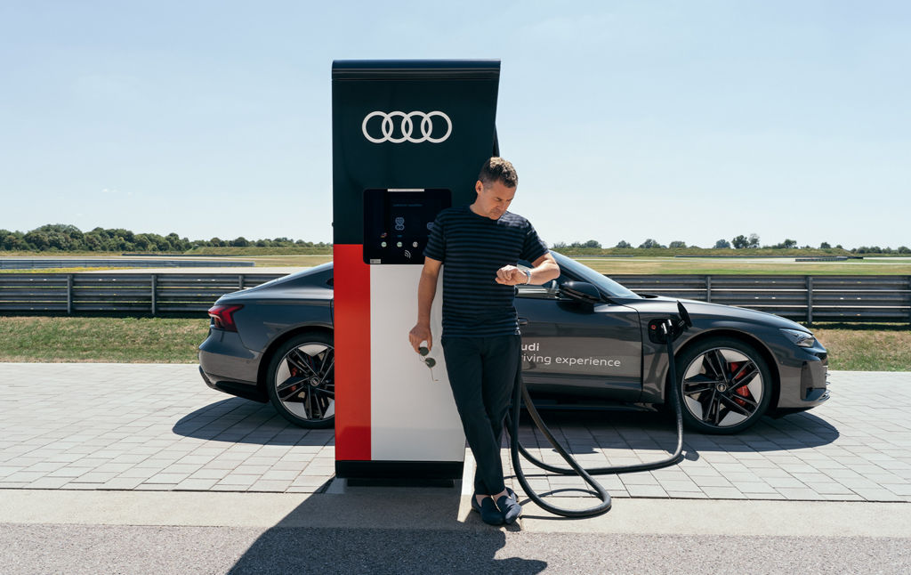 Tom Kristensen lehnt an einer E-Ladesäule, während der RS e-tron GT lädt.