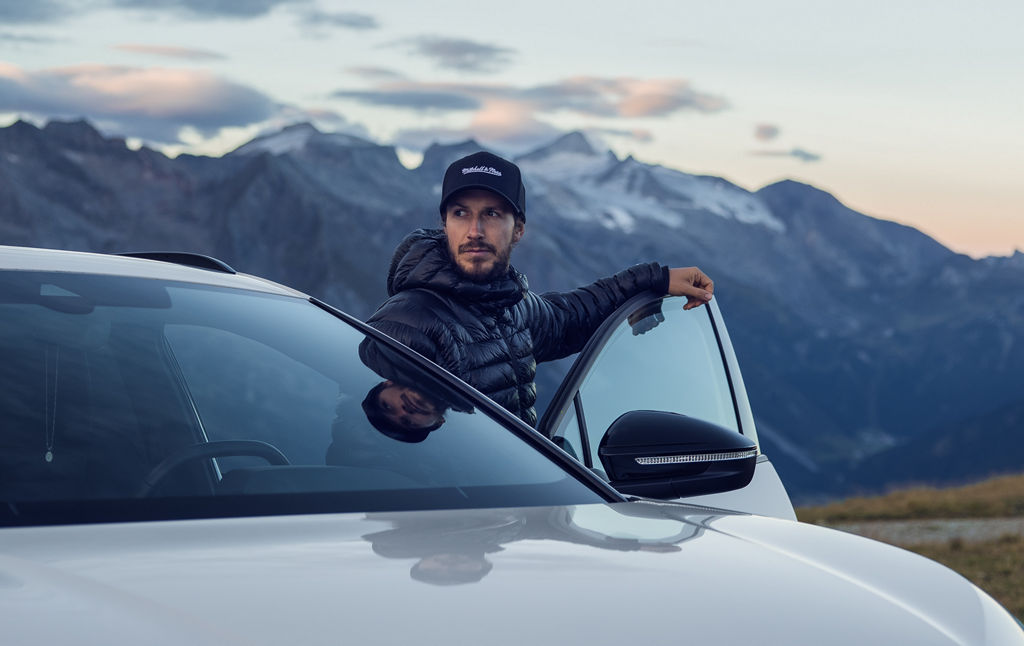 Tom Klocker står med öppen dörr på sin  Audi Q4 e-tron och tittar ut över landskapet.