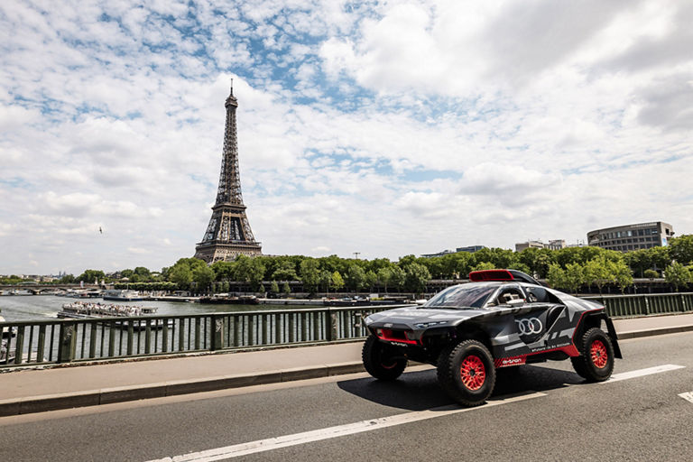 De Audi RS Q e-tron op een brug in Parijs met de Eiffeltoren op de achtergrond.