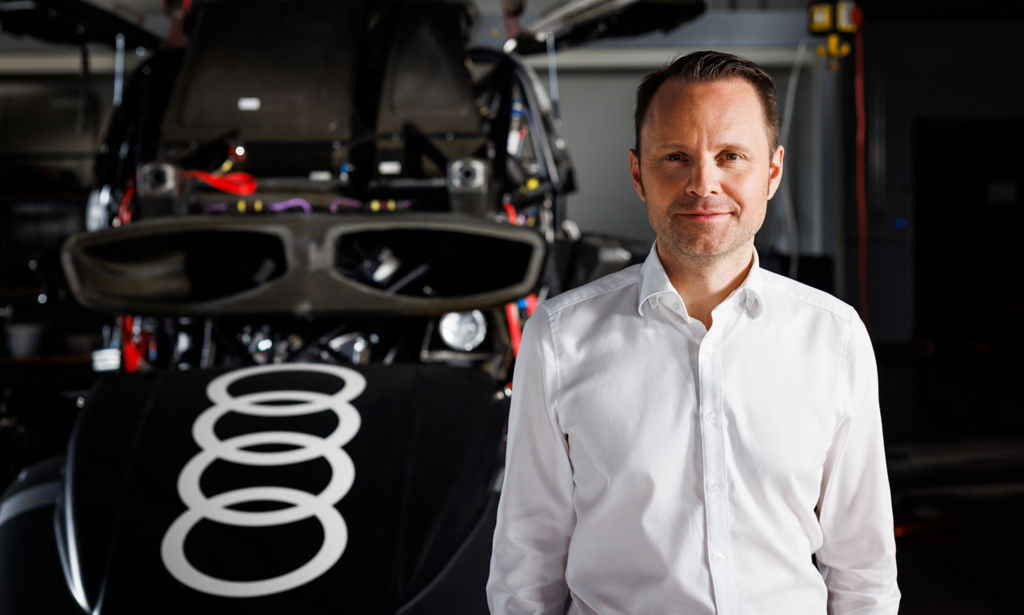 Rolf Michl steht vor den Bauteilen eines Audi RS Q e-tron.