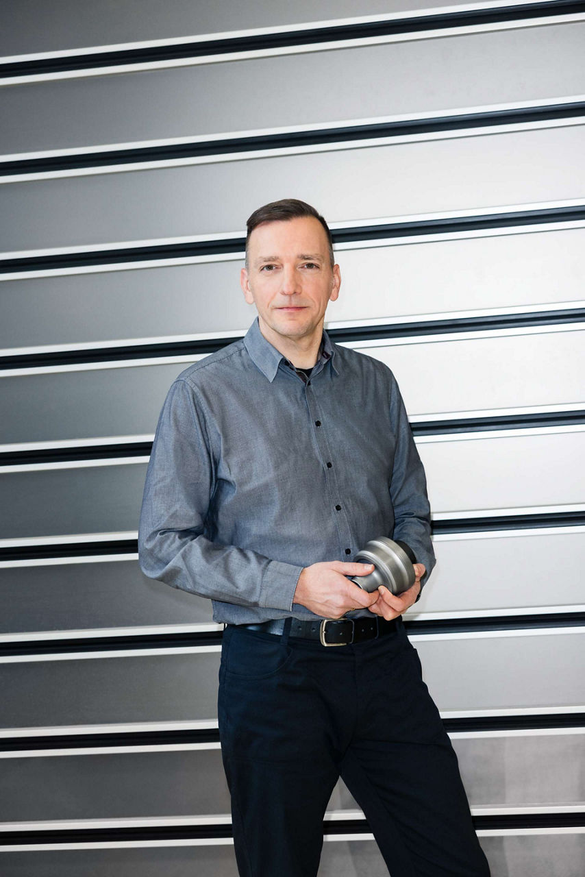 Dieter Weidemann standing in front of a roller shutter, holding a centre differential in his hands.