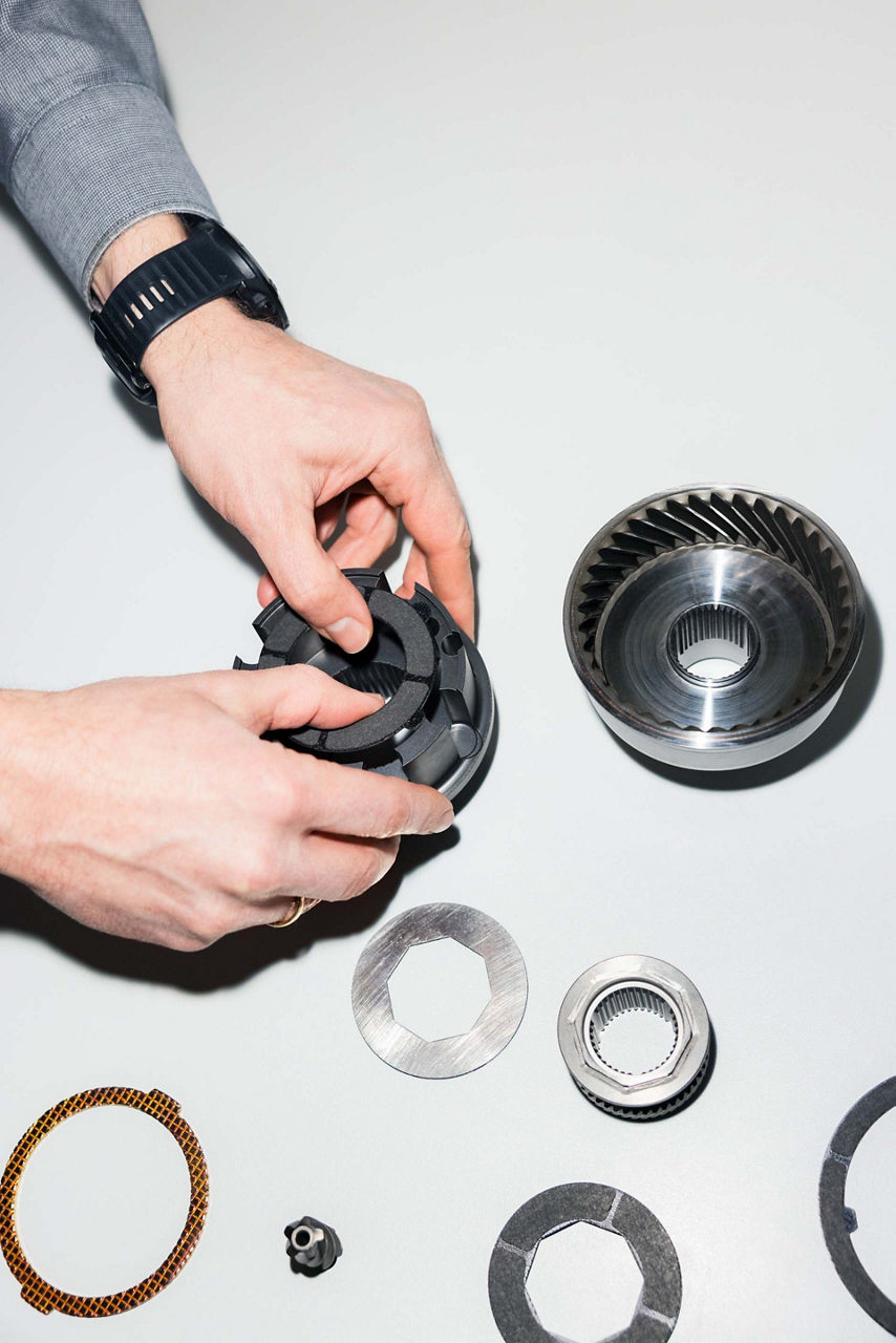 We see Dieter Weidemann’s hands disassembling a centre differential into its component parts. There are a total of eight components on a table.