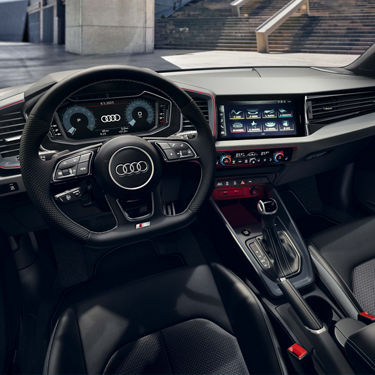Innenraum des Audi A1 Sportback mit sportlichem Lenkrad, digitalem Cockpit und Infotainmentsystem.