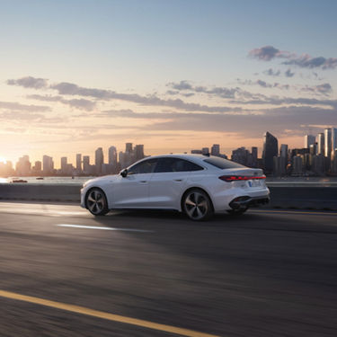 Audi A5 Sedan e-hybrid n a dynamic side view on a street with a big city in the background