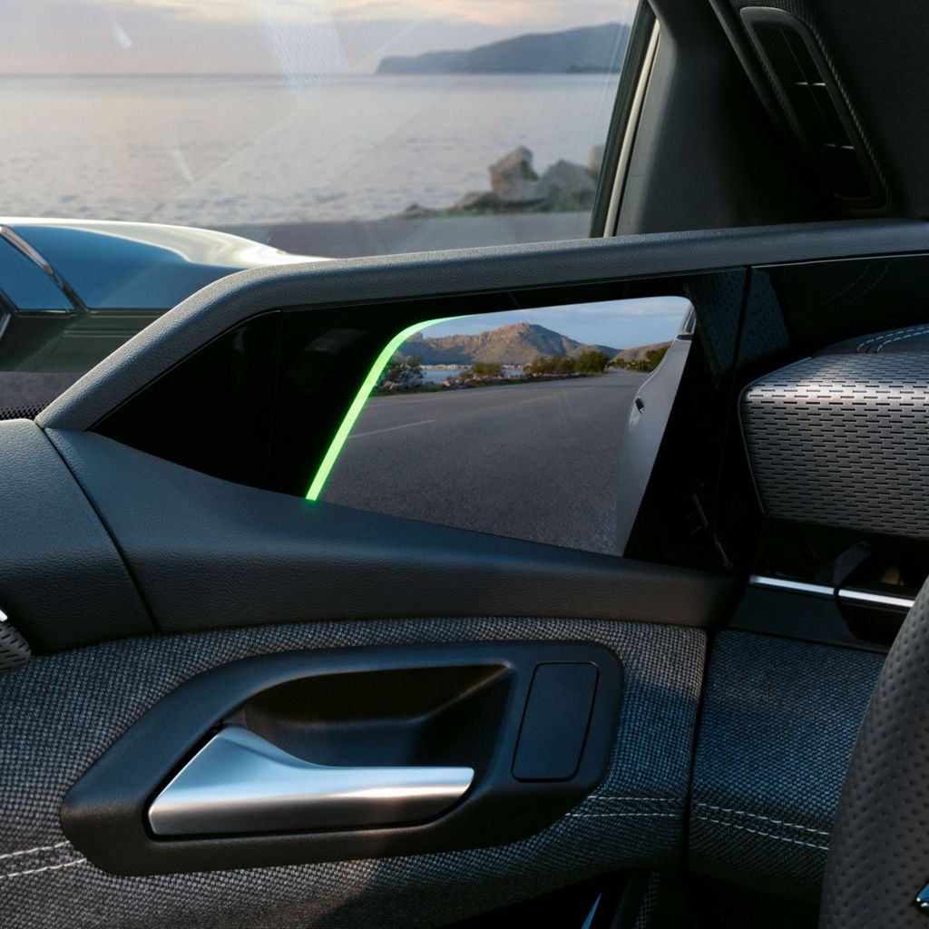 Innenaufnahme eines digitalen Seitenspiegels im Audi A6 Sportback e-tron, zeigt Straße mit Küstenlandschaft.