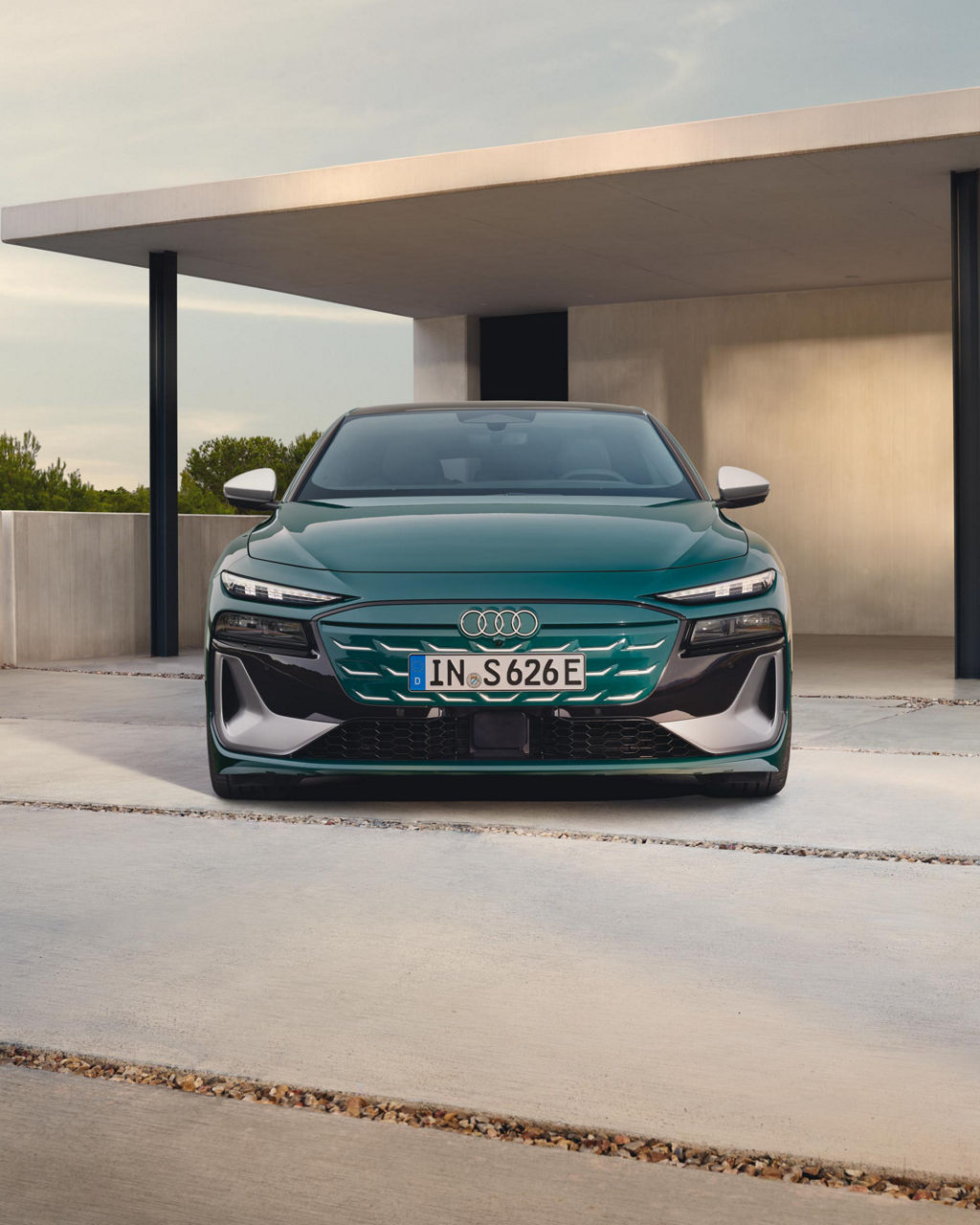 Frontansicht eines grünen Audi S6 Sportback e-tron vor einem modernen Haus mit Flachdach.