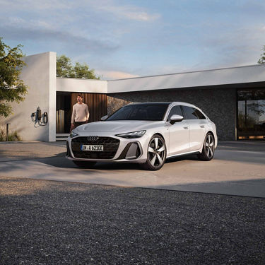 Audi A6 Avant e-hybrid Parkt auf Hauseinfahrt. Model im Hintergrund