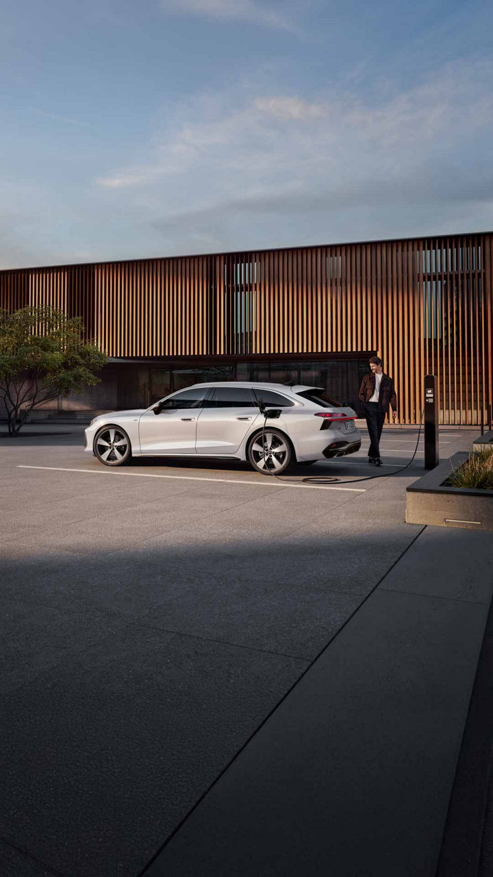 Audi A6 Avant e-hybrid Seiten Ansicht beim Laden mit Model