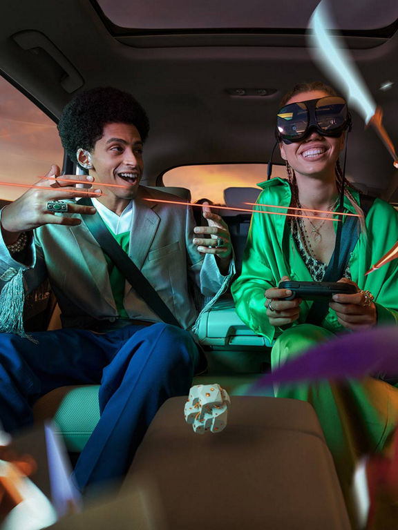 Two passengers experience Holoride gaming in the back of the car