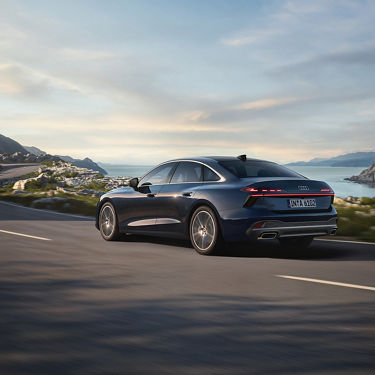 Audi A6 Berline en bleu dans une vue arrière dynamique sur une route devant de l'eau