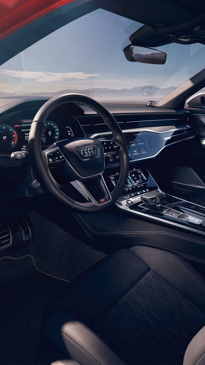 Audi-Cockpit mit Digitaltacho, großem Touchscreen und schwarzen Ledersitzen, Blick durch Beifahrerfenster.