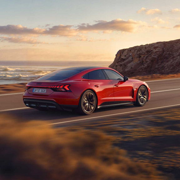 Audi e-tron GT quattro dynamische Seitenansicht auf einer Straße in den Sonnenuntergang