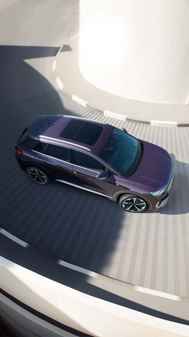 Top-down view of a purple SUV on a spiral white ramp casting long shadows.