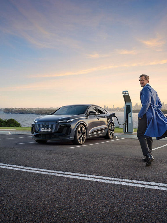 Audi Q6 Sportback e-tron laddas, en man står bredvid