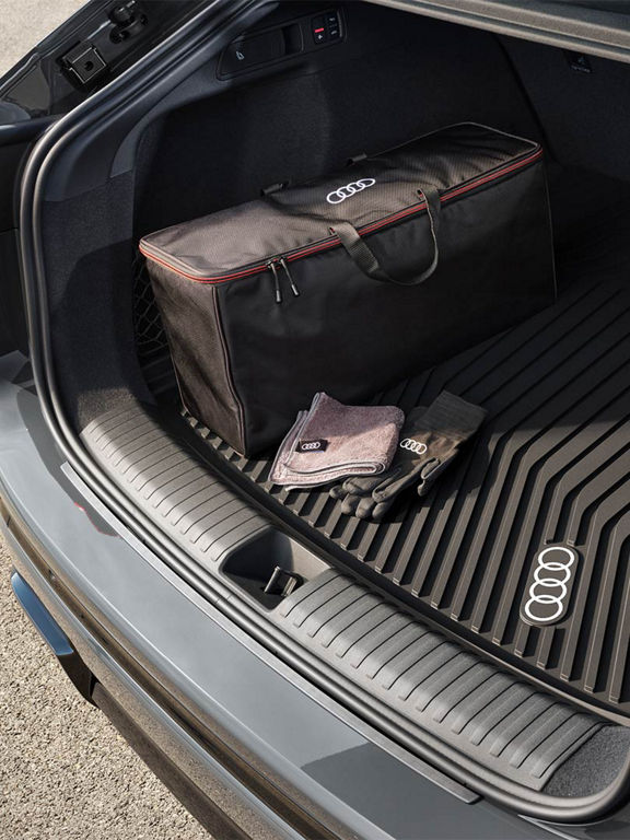 Audi Q6 Sportback e-tron med formpassande skydd i bagageutrymmet. På skyddet ligger en väska, ett par handskar och en handduk.