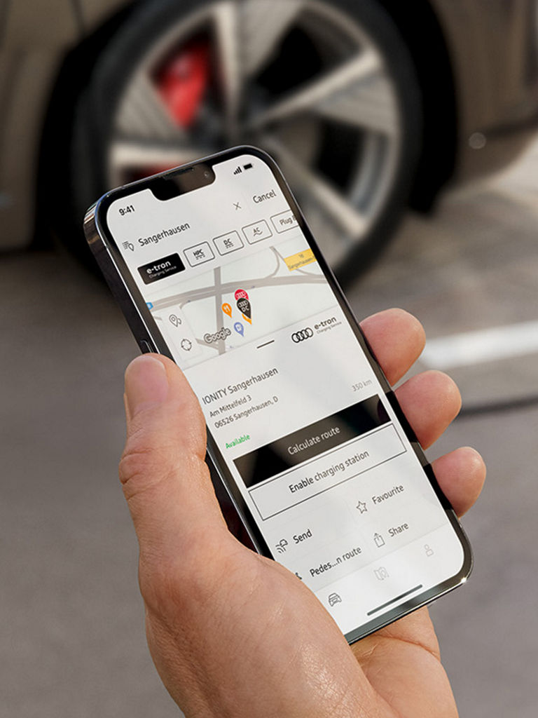 Mies älypuhelimen kanssa Audi Q8 e-tronin edessä