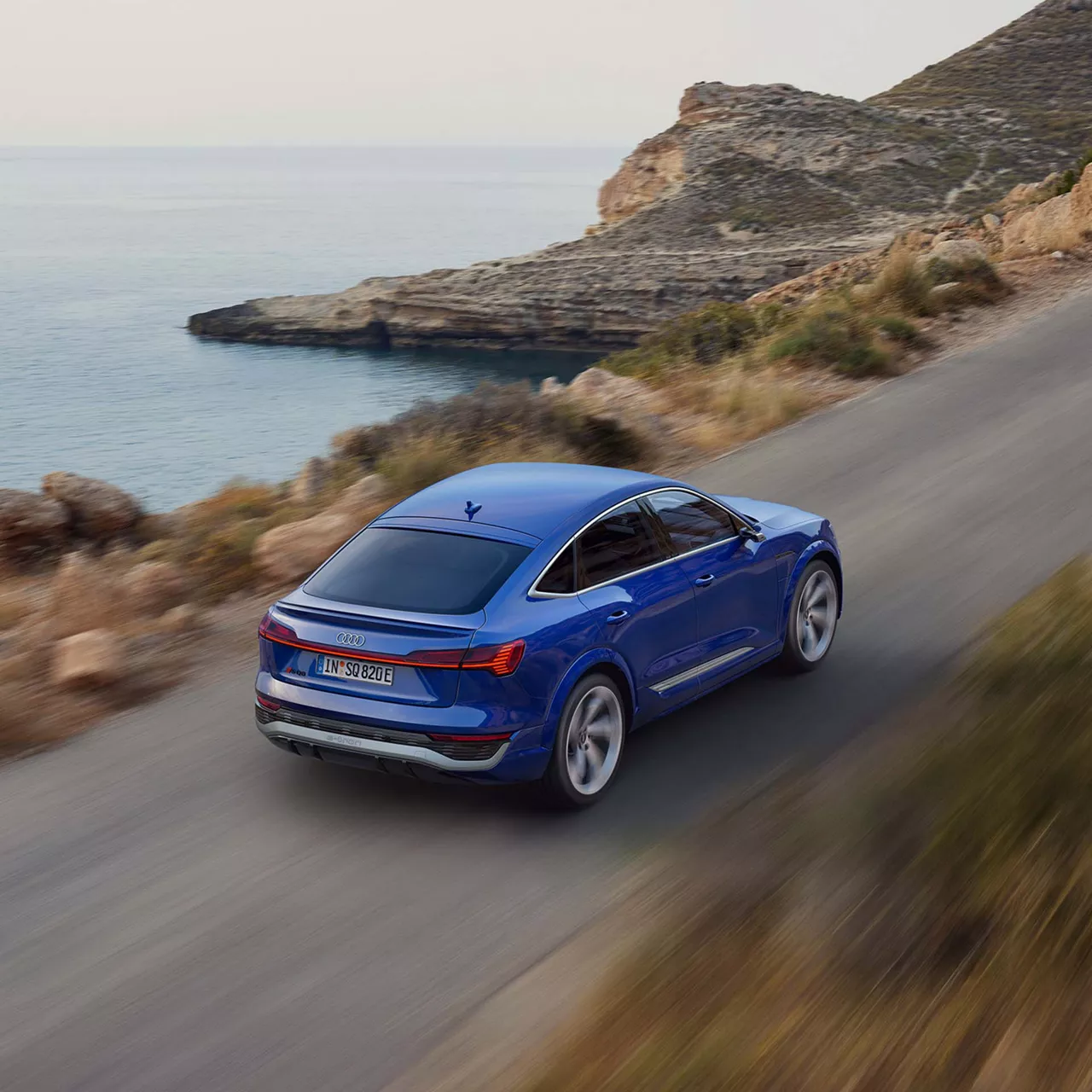 Ein blauer Audi auf einer Straße am Wasser 