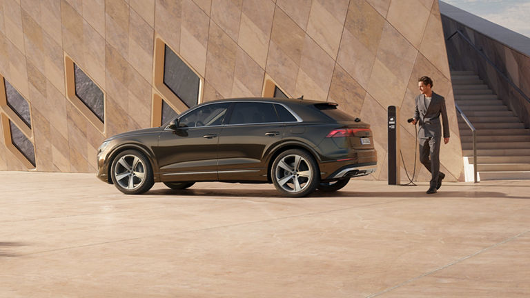 Q8 SUV TFSI e widok z boku z osobą, która chce naładować samochód