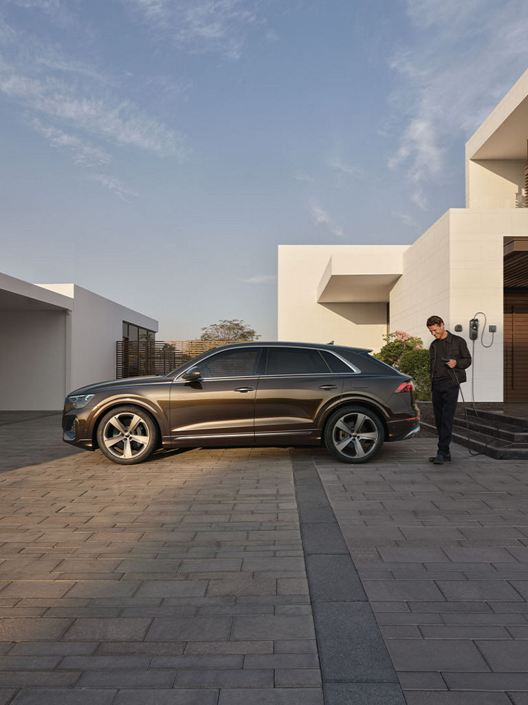 Man charging his Audi Q8 SUV TFSI e at home