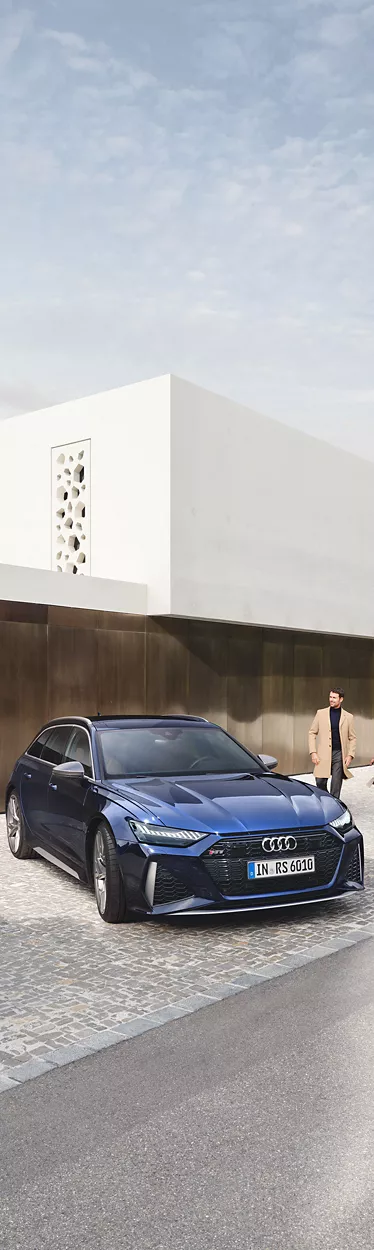 Mann und Frau gehen auf Audi RS 6 Avant zu