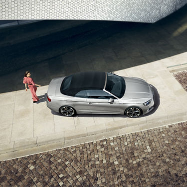 Frau läuft hinter Audi A5 Cabriolet lang