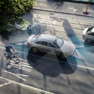 Fahrrad fährt neben Audi A6 Limousine im Stadtverkehr