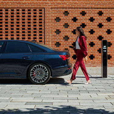 Frau läuft am Kofferraum der Audi A6 Limousine TFSI e vorbei