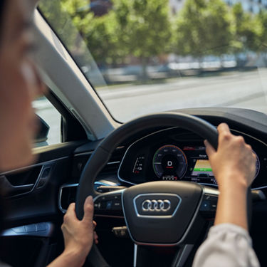 Frau sitzt hinter dem Steuer eines Audi A6 