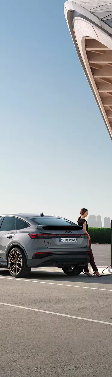 Audi Q4 Sportback e-tron steht vor einer Skyline und lädt an Ladesäule auf