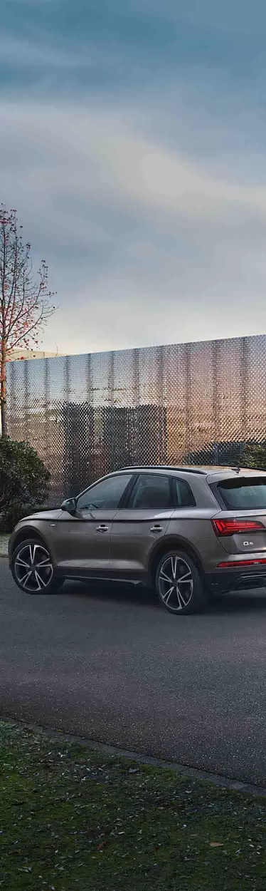 Vista lateral de un Audi Q5 con una modelo mujer al lado.