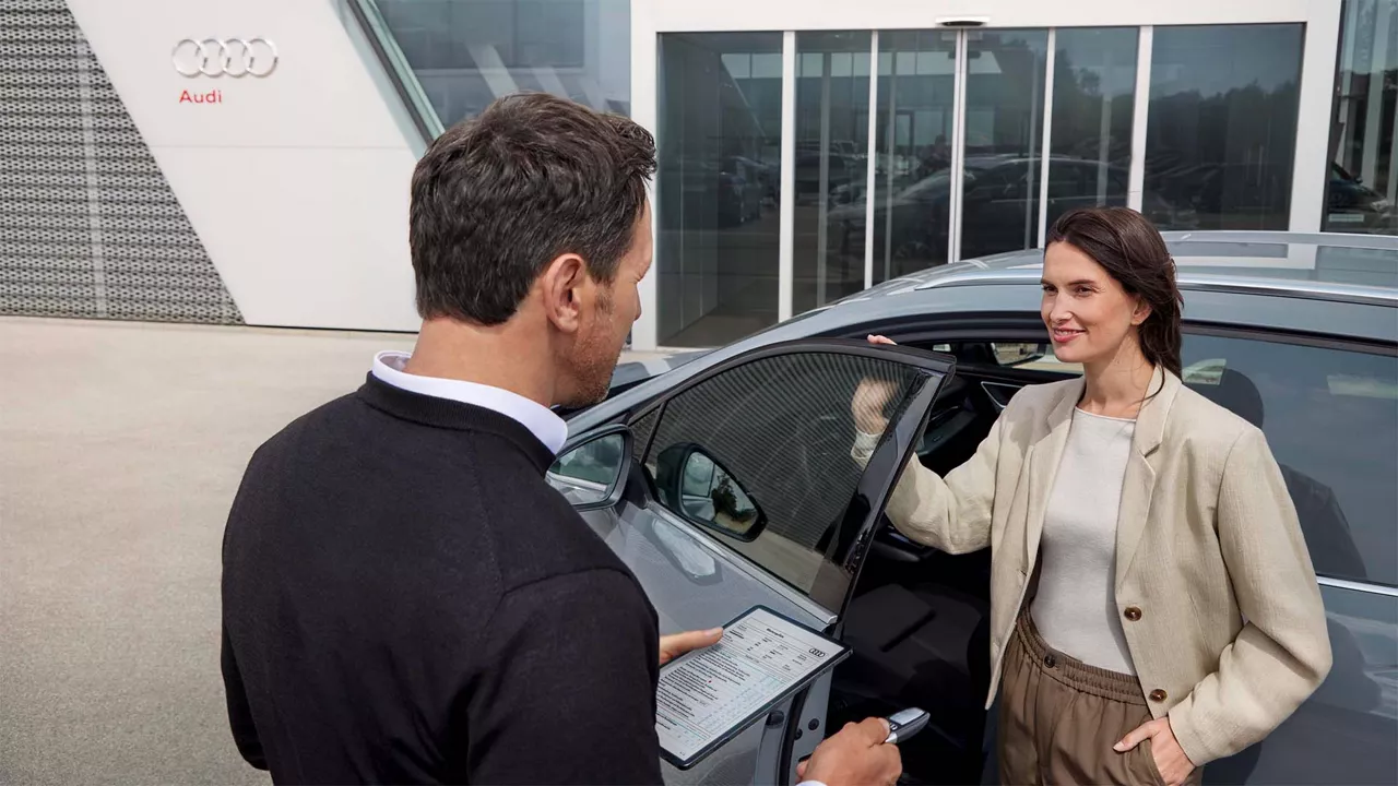 Eine Frau und ein Mann unterhalten sich neben einem Auto