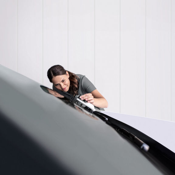 A female Audi Service engineer working the windscreen of an Audi.