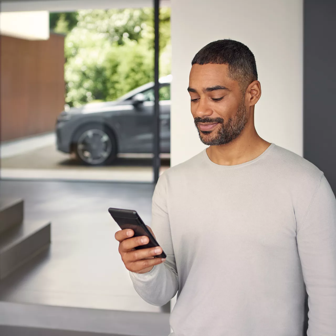   Närbild av en man som håller i en telefon framför en Audi Q4 e-tron