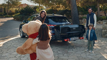 Eine Familie steht vor einem bepackten Audi.