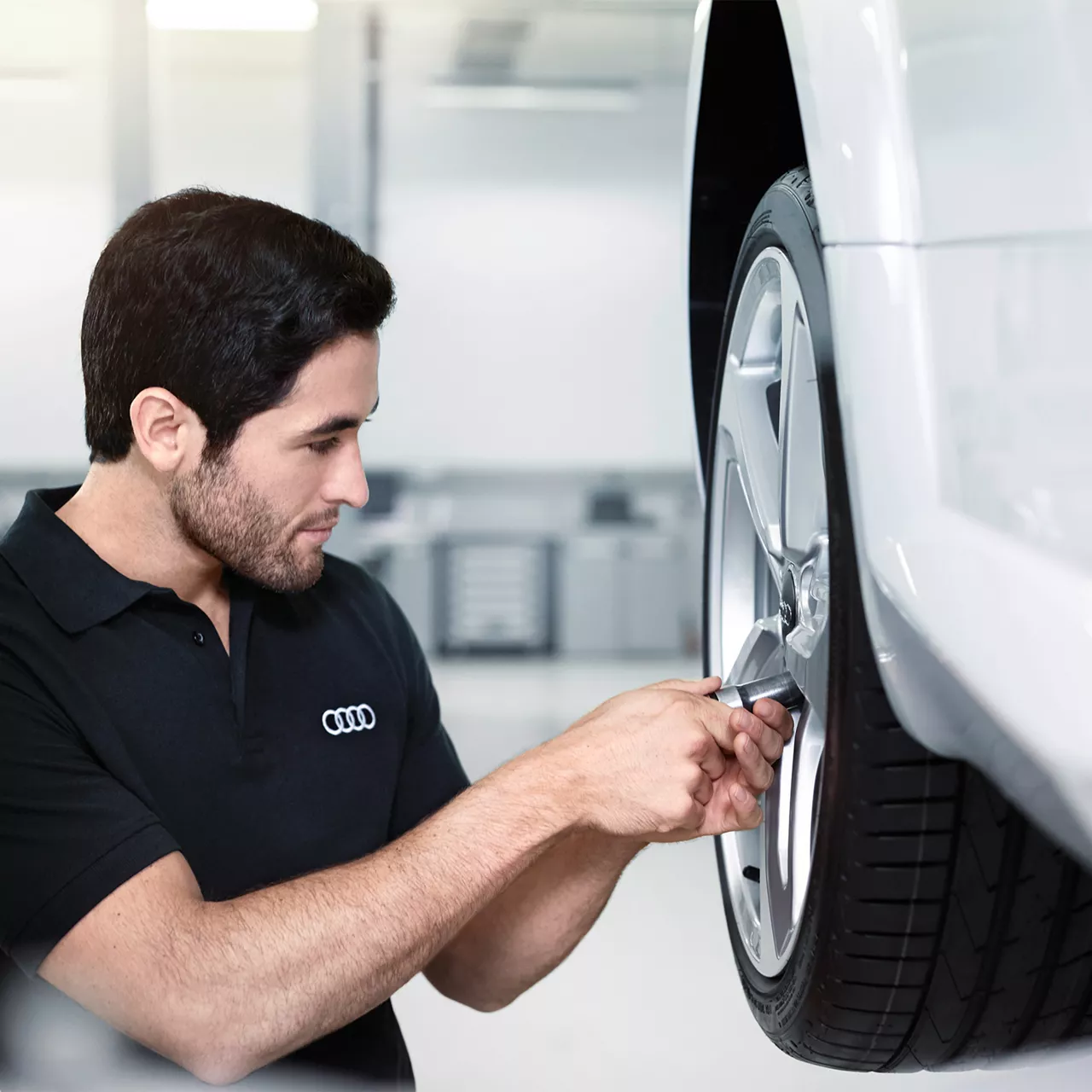 Audi servicepersonal som byter däck på ett backdäck på en vit Audibil